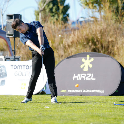 Golfer swinging at a tee in front of a HIRZL event banner